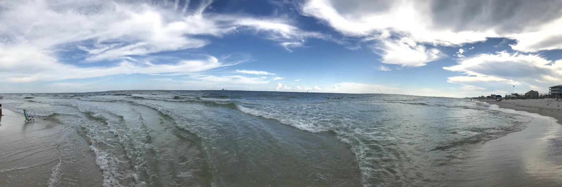 Waves meeting a quiet sandy shoreline beneath an open sky